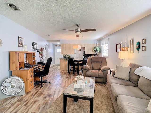 living room with a textured ceiling, light hardwood / wood-style flooring, and ceiling fan