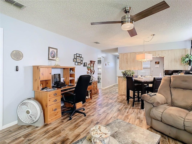 office space featuring ceiling fan, light hardwood / wood-style floors, and a textured ceiling