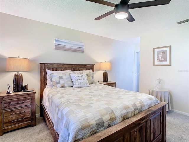 bedroom featuring light carpet, a textured ceiling, and ceiling fan