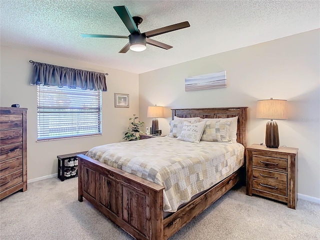 bedroom with ceiling fan, light colored carpet, and a textured ceiling