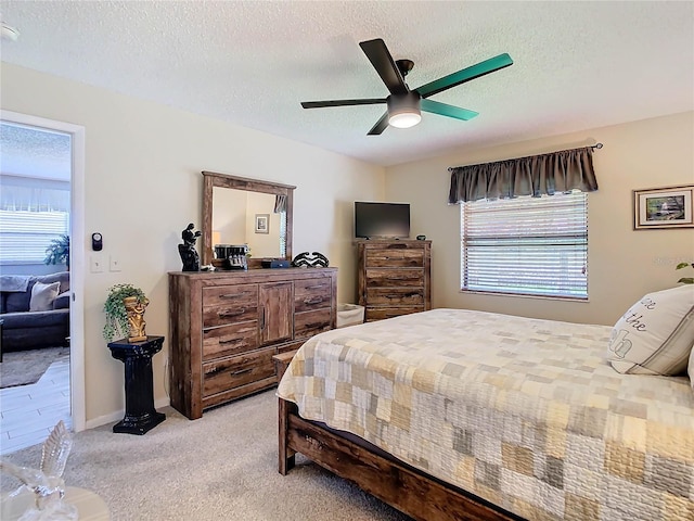 bedroom with light carpet, a textured ceiling, multiple windows, and ceiling fan