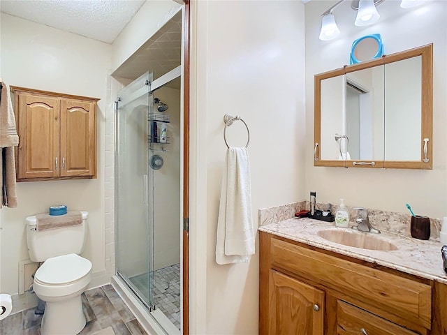 bathroom with vanity, hardwood / wood-style flooring, toilet, a textured ceiling, and an enclosed shower