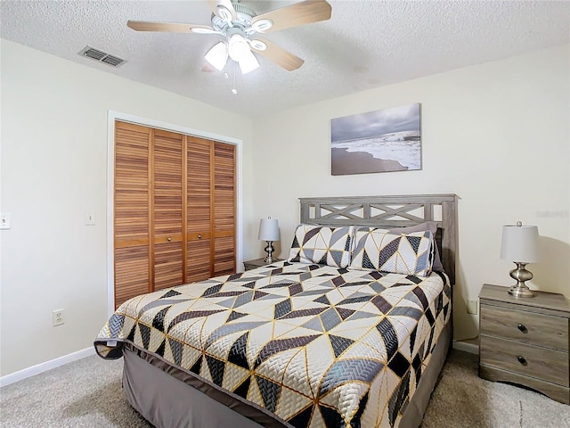 carpeted bedroom featuring ceiling fan, a closet, and a textured ceiling