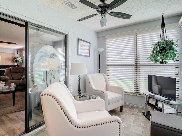 living area with ceiling fan and a textured ceiling