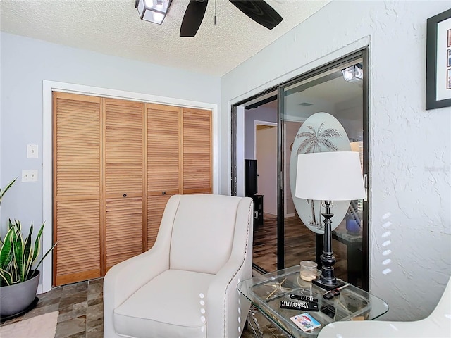 sitting room with ceiling fan and a textured ceiling