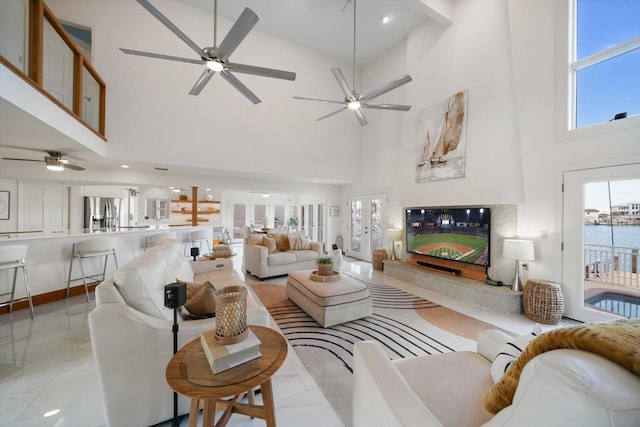 living room with a high ceiling, ceiling fan, and light tile patterned flooring