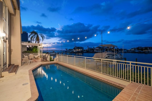 pool at dusk featuring a water view