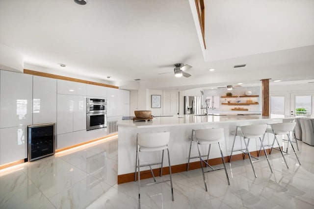 kitchen featuring a breakfast bar area, wine cooler, white cabinets, and stainless steel appliances