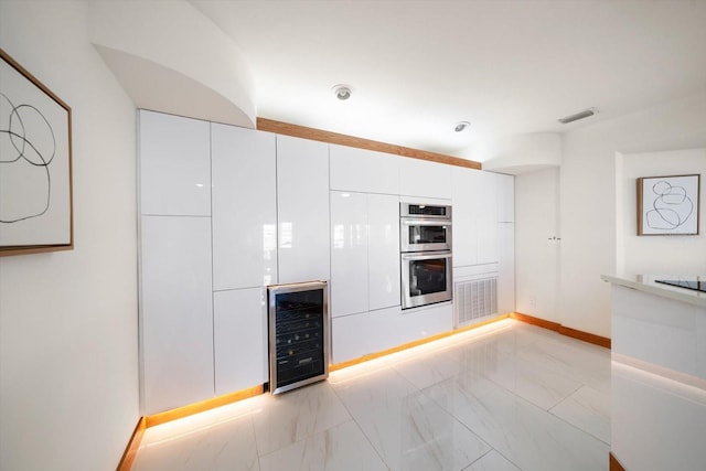 18 Winston Dr, Belleair, FL 33756 - kitchen with beverage cooler, double oven, white cabinetry, baseboards, and light marble finish floors
