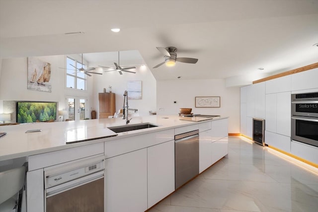 kitchen with appliances with stainless steel finishes, beverage cooler, sink, high vaulted ceiling, and white cabinetry