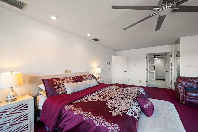 carpeted bedroom featuring ceiling fan and a barn door