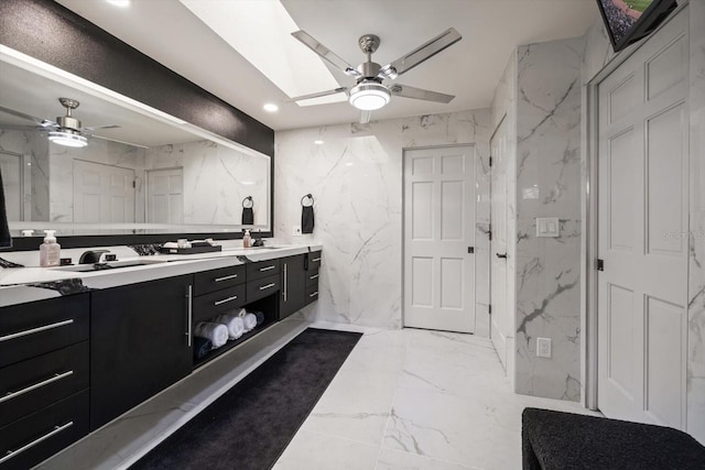 18 Winston Dr, Belleair, FL 33756 - bathroom with a ceiling fan, marble tiled floors, double vanity, stone wall, and tile walls