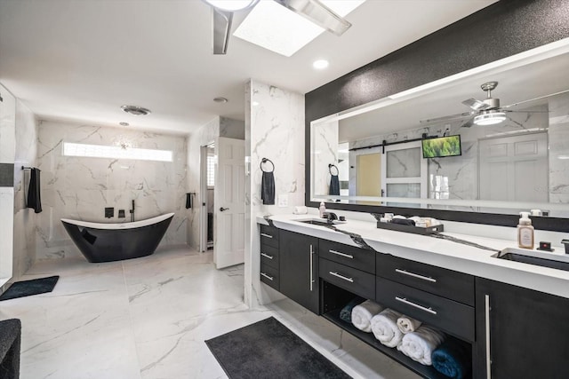 bathroom with a skylight, vanity, a tub to relax in, and ceiling fan