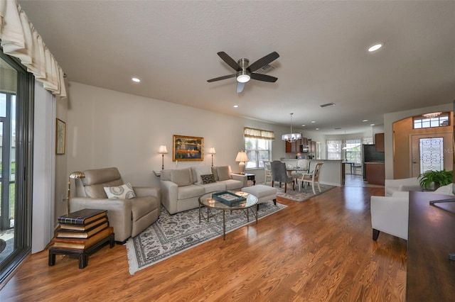 living room featuring ceiling fan with notable chandelier and dark hardwood / wood-style flooring