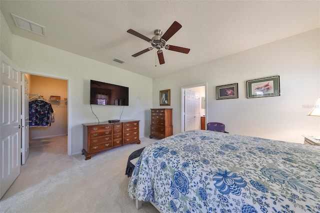 carpeted bedroom featuring a walk in closet, ceiling fan, a closet, and ensuite bathroom