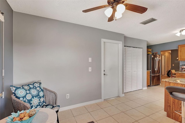 kitchen with stainless steel fridge, a textured ceiling, light tile patterned floors, and ceiling fan