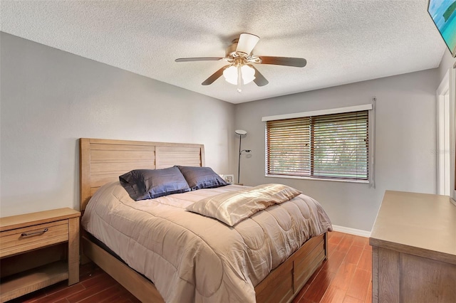 bedroom with a textured ceiling, dark hardwood / wood-style flooring, and ceiling fan