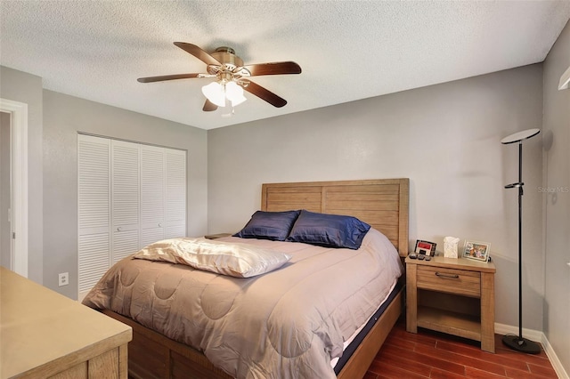 bedroom with a textured ceiling, a closet, dark wood-type flooring, and ceiling fan