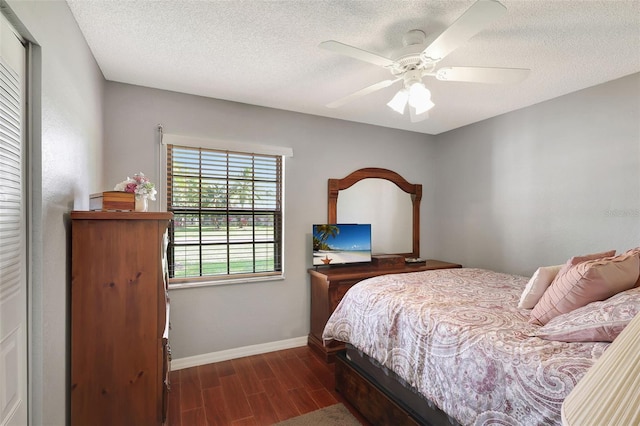 bedroom with a textured ceiling, ceiling fan, and dark wood-type flooring