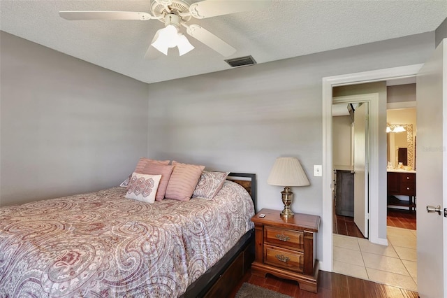 bedroom featuring a textured ceiling, ensuite bath, ceiling fan, and light tile patterned flooring