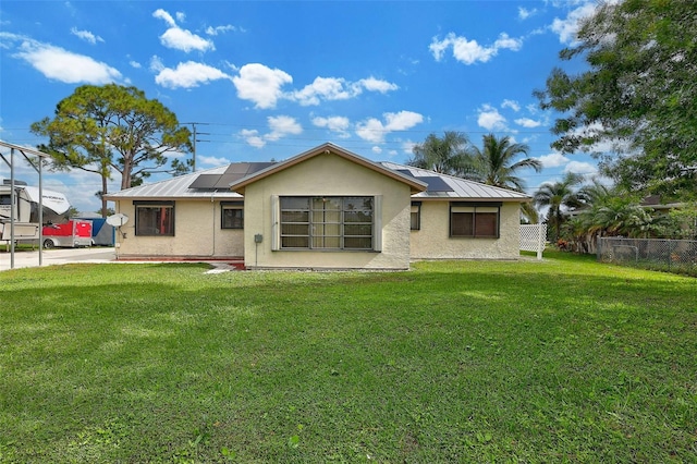 rear view of house with solar panels and a lawn