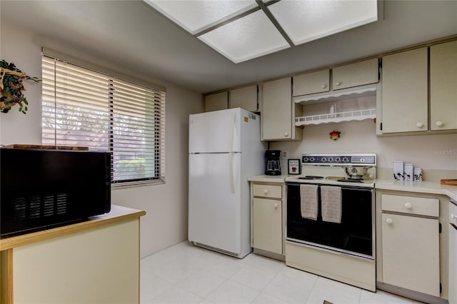 kitchen with electric range, cream cabinets, and white fridge