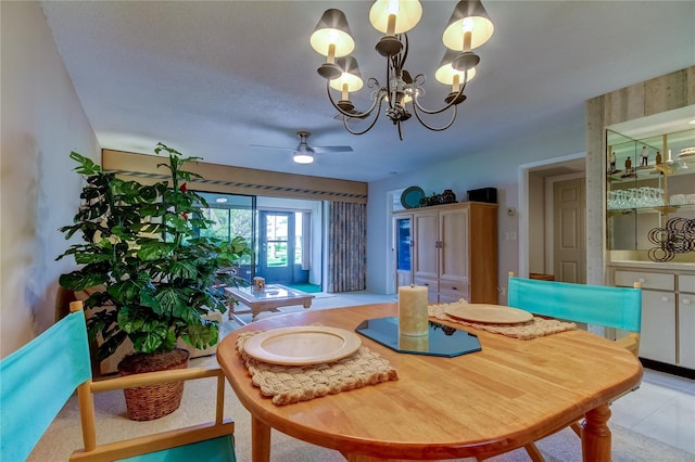 tiled dining area featuring a textured ceiling and ceiling fan with notable chandelier