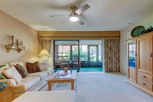 living room featuring ceiling fan, light colored carpet, and a textured ceiling