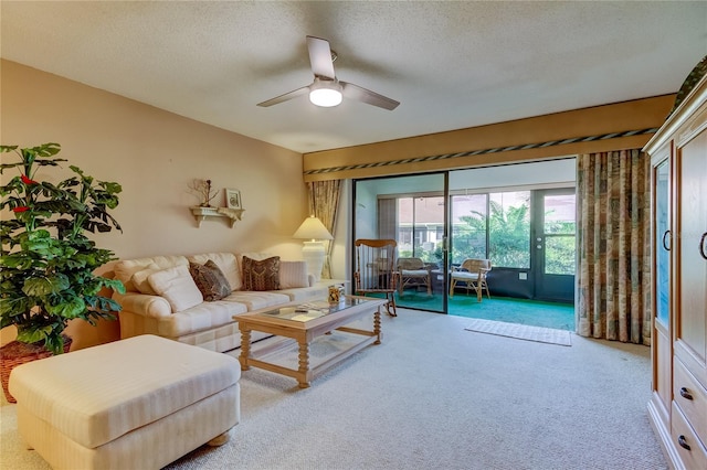 living room with a textured ceiling, carpet floors, and ceiling fan