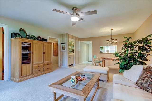 carpeted living room featuring ceiling fan with notable chandelier