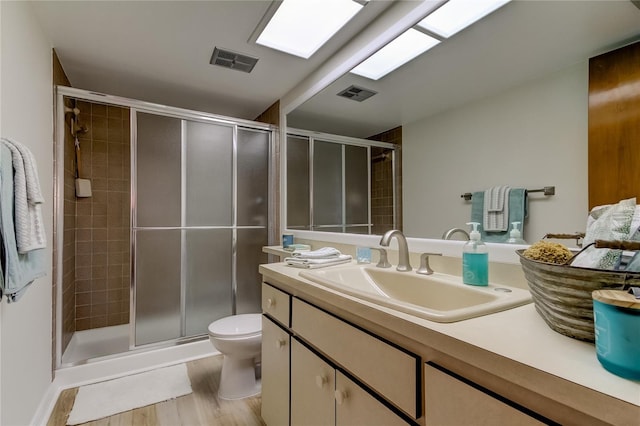 bathroom featuring wood-type flooring, vanity, toilet, and a shower with shower door