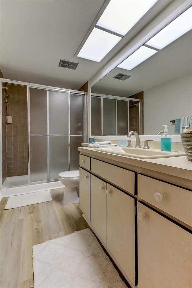 bathroom featuring hardwood / wood-style floors, vanity, a shower with door, and toilet