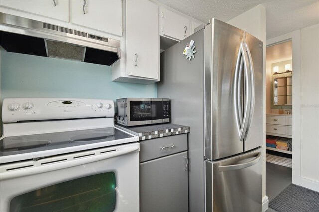 kitchen with stainless steel fridge, white cabinetry, and white electric stove