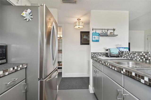 kitchen featuring decorative backsplash, stainless steel appliances, concrete flooring, and gray cabinetry