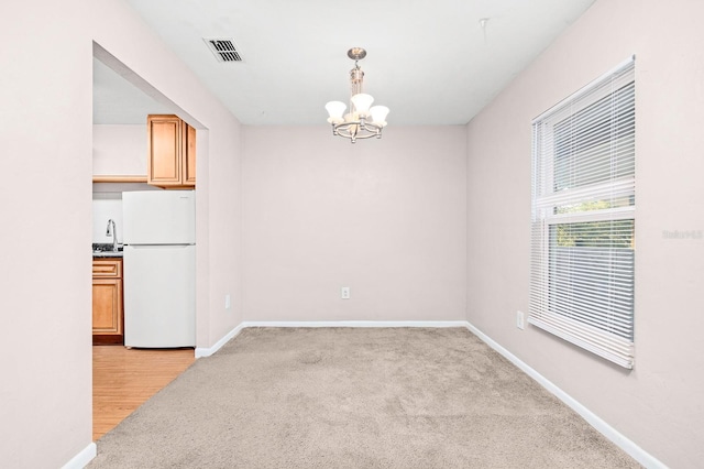 unfurnished dining area with an inviting chandelier, visible vents, and baseboards