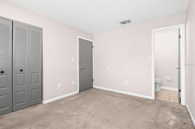 unfurnished bedroom with visible vents, ensuite bath, a closet, carpet, and baseboards