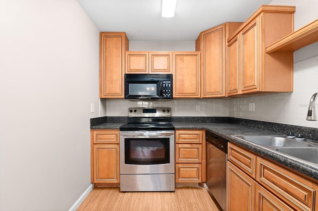 kitchen featuring light wood-type flooring, decorative backsplash, dark countertops, and appliances with stainless steel finishes