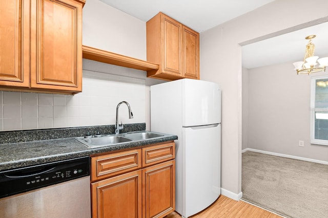 kitchen with freestanding refrigerator, a sink, stainless steel dishwasher, dark countertops, and tasteful backsplash