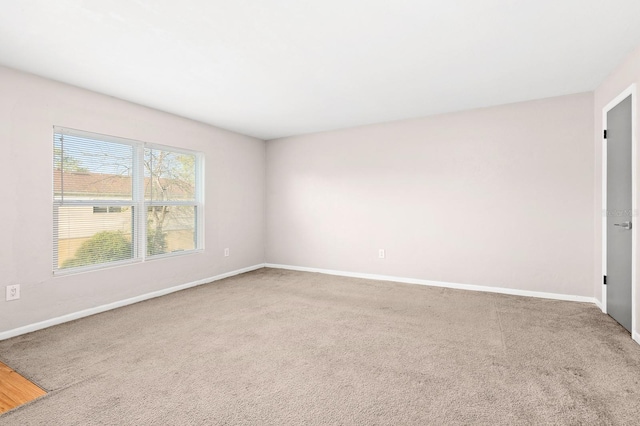 spare room featuring carpet and baseboards