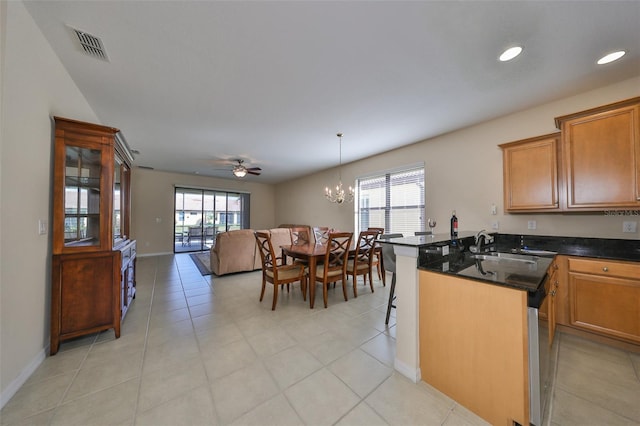 kitchen with a kitchen breakfast bar, ceiling fan with notable chandelier, decorative light fixtures, an island with sink, and light tile patterned flooring