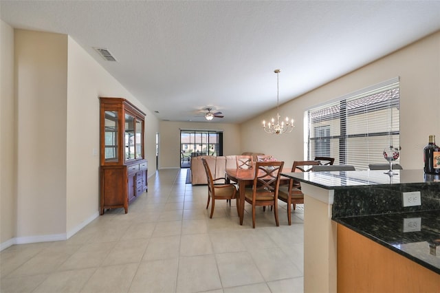 tiled dining area with ceiling fan with notable chandelier and a textured ceiling