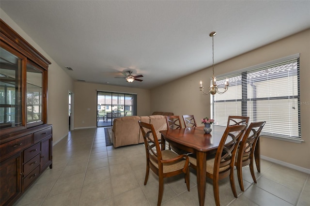 dining space with ceiling fan with notable chandelier and light tile patterned flooring