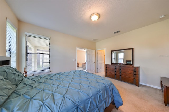 bedroom with light colored carpet, a textured ceiling, and multiple windows