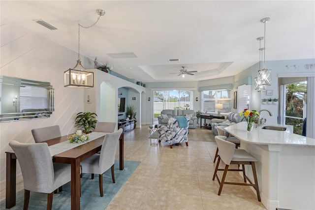 dining area featuring a tray ceiling, ceiling fan, sink, and light tile patterned floors