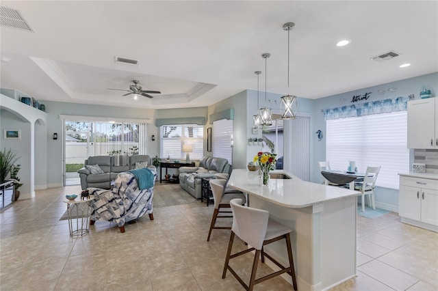 kitchen with white cabinets, a breakfast bar, pendant lighting, and a center island with sink