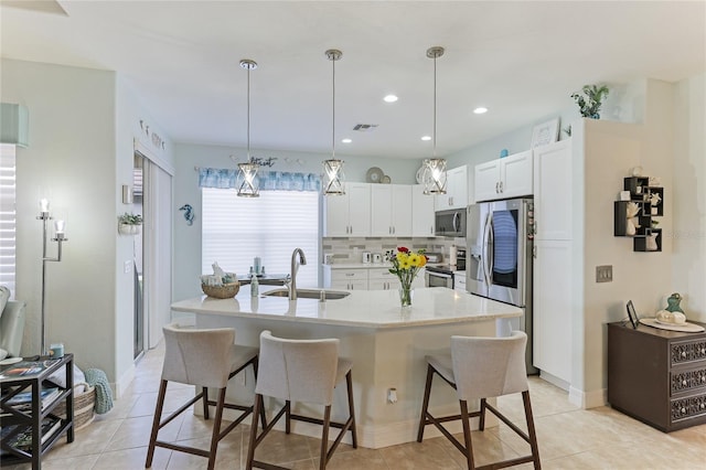 kitchen with sink, hanging light fixtures, decorative backsplash, white cabinetry, and stainless steel appliances