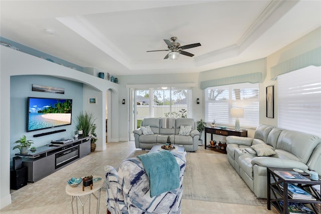 living room with a tray ceiling, ceiling fan, and ornamental molding