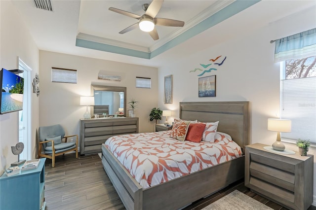 bedroom featuring ceiling fan, wood-type flooring, ornamental molding, and a tray ceiling