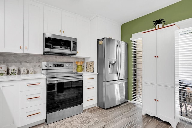 kitchen with decorative backsplash, white cabinets, light hardwood / wood-style floors, and appliances with stainless steel finishes