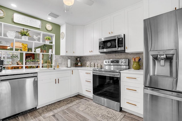 kitchen with white cabinetry, stainless steel appliances, and light wood-type flooring